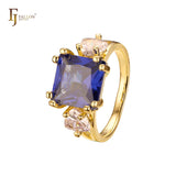 Anillo de compromiso en oro de 14 quilates con solitario de gran corte esmeralda y circonitas cúbicas coloridas en ambos lados, con dos circonitas blancas.