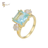 Anillo de compromiso en oro de 14 quilates con solitario de gran corte esmeralda y circonitas cúbicas coloridas en ambos lados, con dos circonitas blancas.